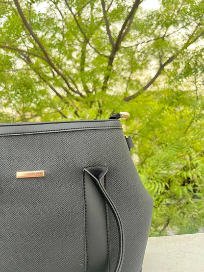 Graciza black Aero shoulder bag with textured faux leather, flared wing design, and minimalist gold bar hardware.