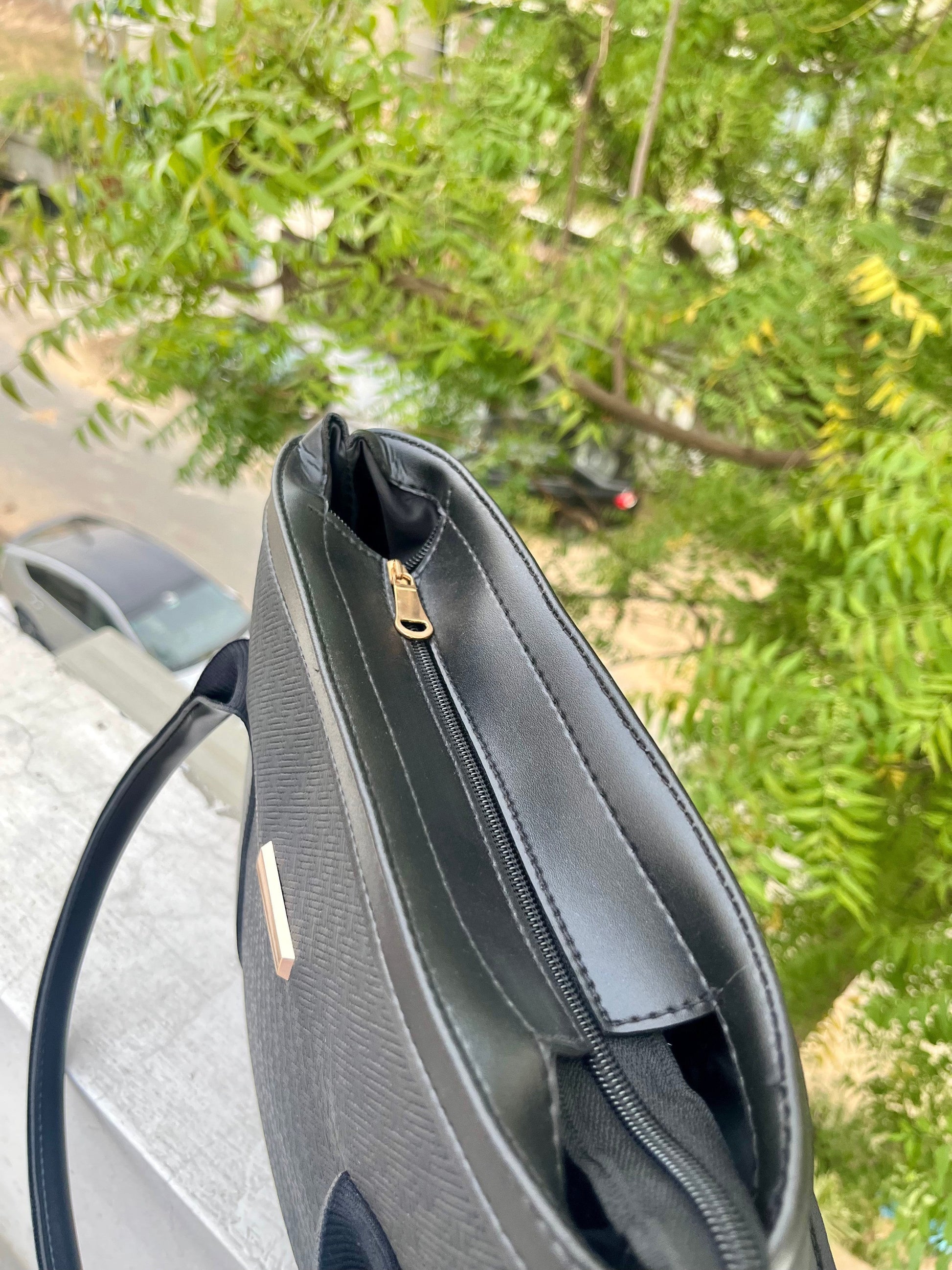 Graciza black faux leather Aero shoulder bag with textured finish, gold bar hardware, and structured wing design.