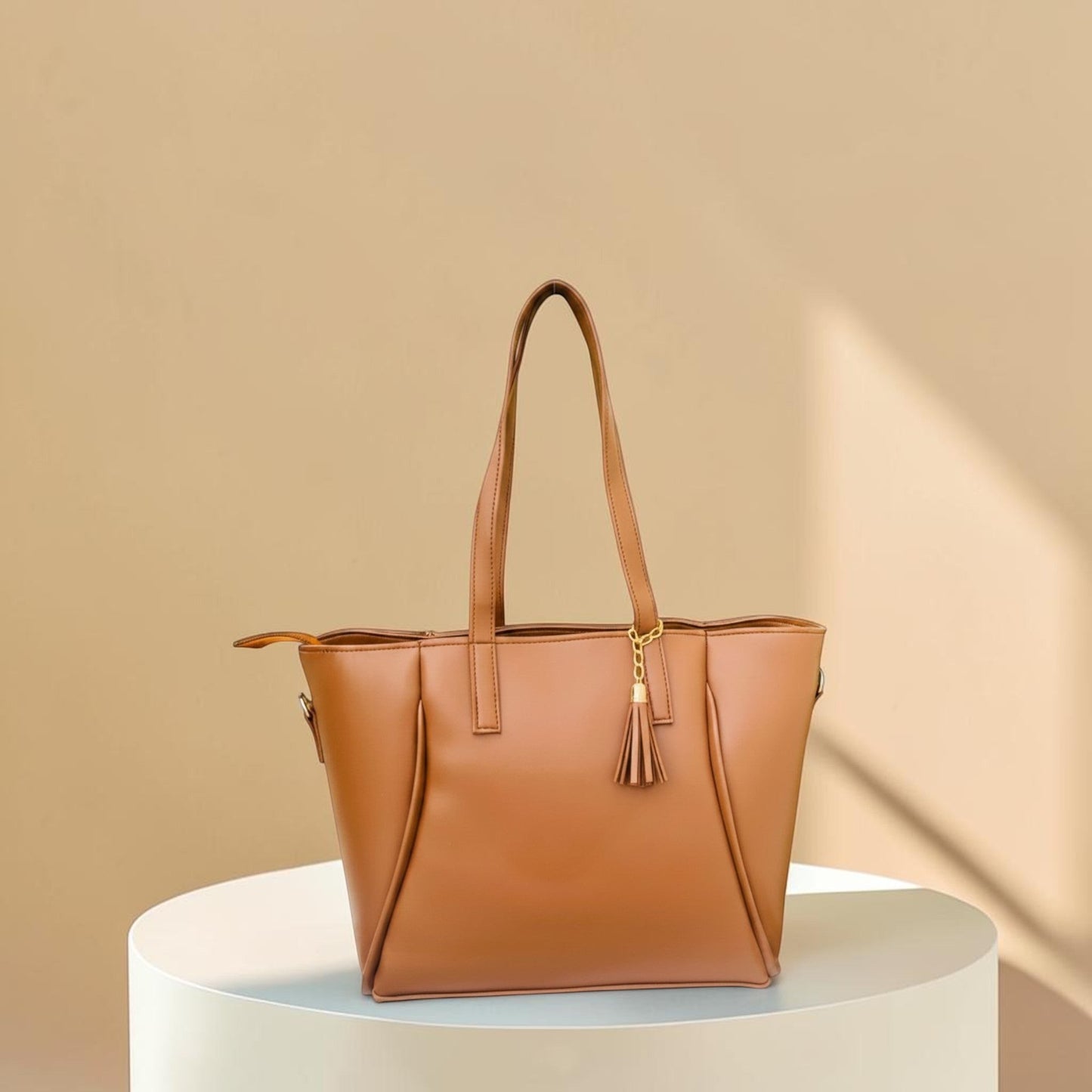 Graciza Aura brown faux leather tote bag with gold-tone hardware and decorative tassel on a white pedestal.