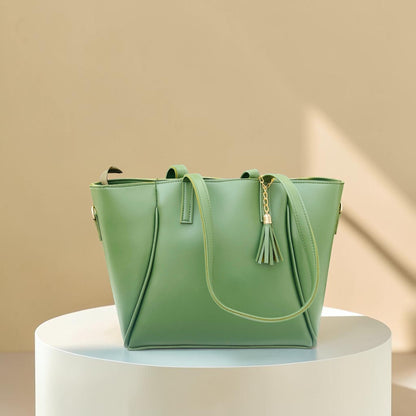 Graciza Aura green faux leather tote bag with gold hardware and decorative tassel on a white pedestal
