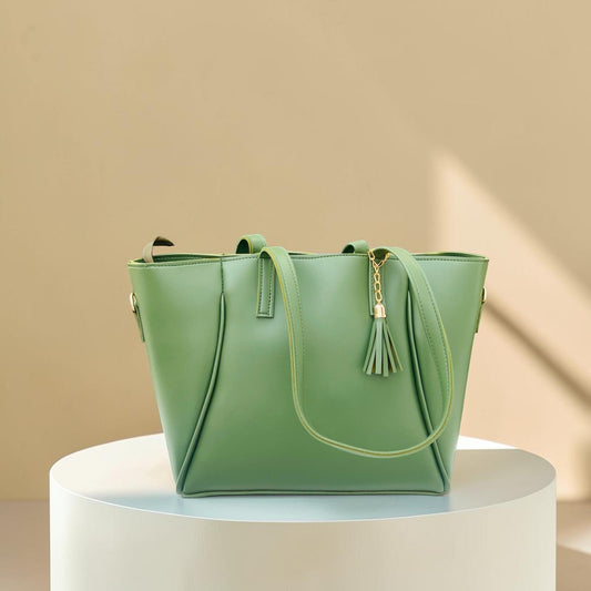 Graciza Aura green faux leather tote bag with gold hardware and decorative tassel on a white pedestal