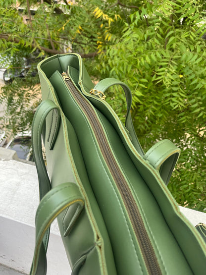 Graciza Aura green faux leather tote bag with gold-tone zipper and double handles, set against a leafy outdoor backdrop