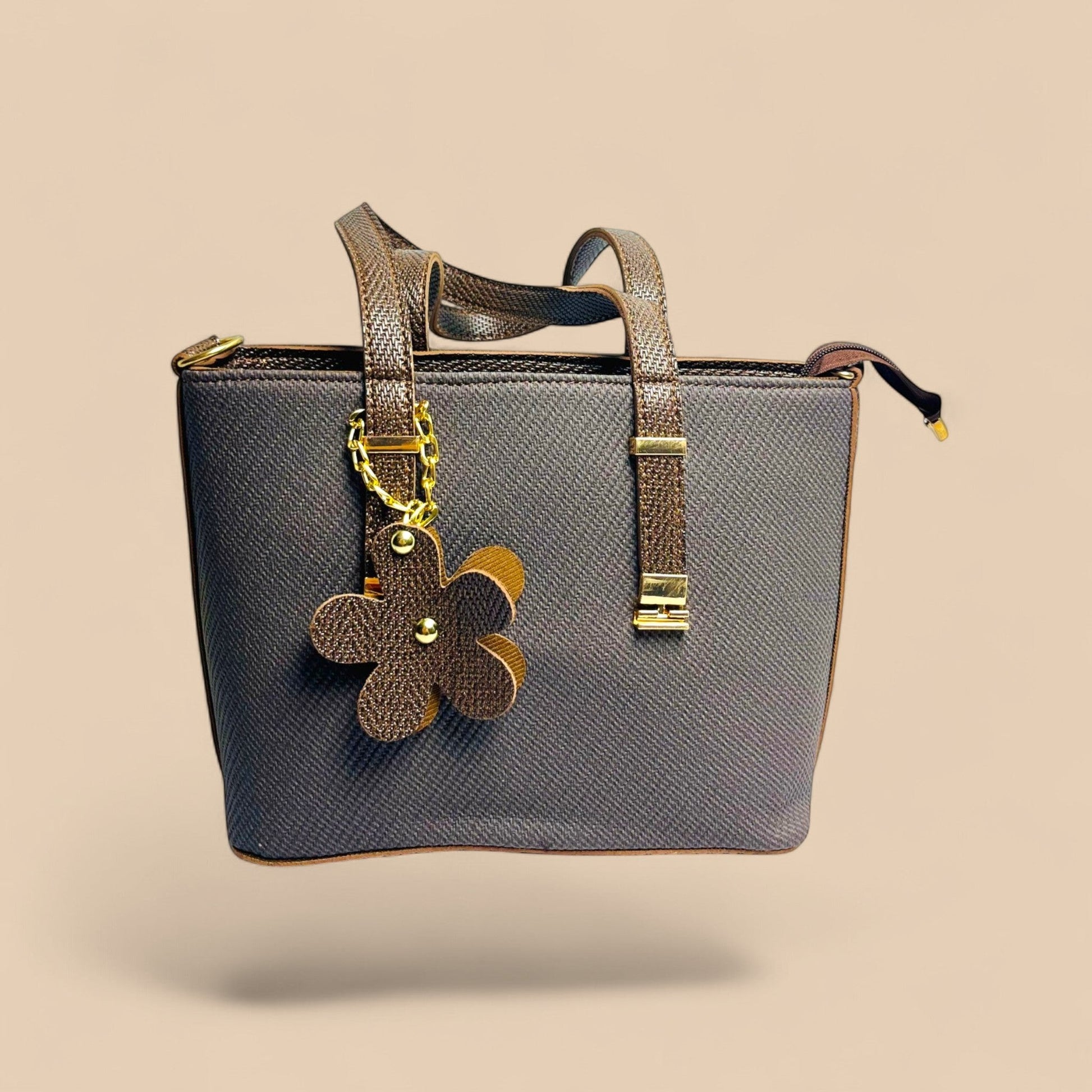 Graciza brown faux leather handbag with twin handles, floral charm, and zip closure for office or casual use.
