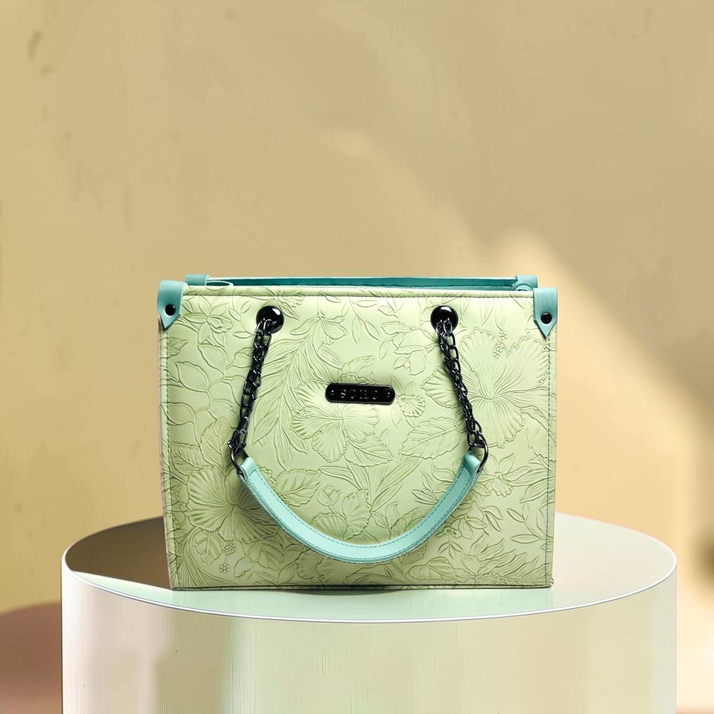 Graciza Flora light mint faux leather shoulder bag with floral embossing, black chain handles, and top-zip closure.